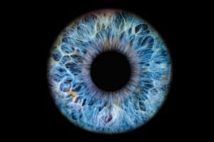 Close up image of a bright blue eye on a black background