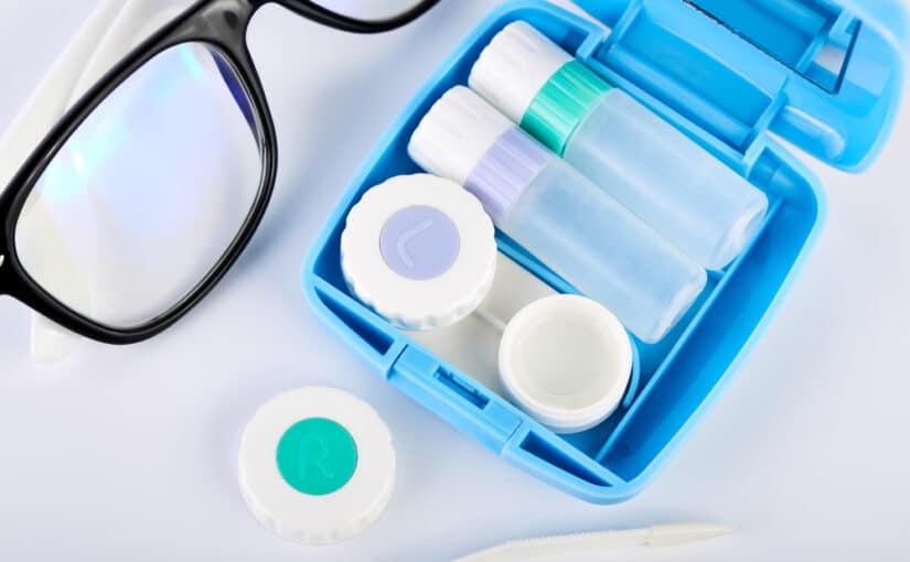 Pair of black rimmed eyeglasses, next to a contact lens case